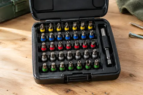 Coffret noir ouvert avec embouts de vissage codés par couleur et porte-embout magnétique sur un établi